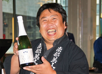 「南部美人あわさけスパークリング」を手に笑顔を浮かべる久慈浩介氏