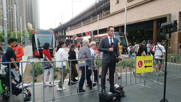 長い行列ができたサーキュラ・キー駅前で中継を行う地元テレビ局のリポーター