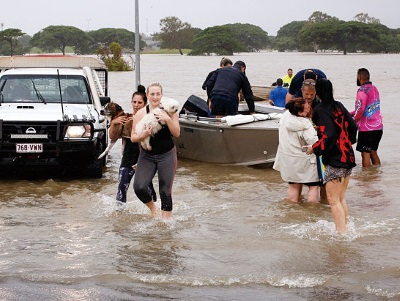 大規模な洪水に襲われたQLD州東部タウンズビルで2月4日、飼い犬を抱いてボートで避難する住民たち（Photo: AFP）