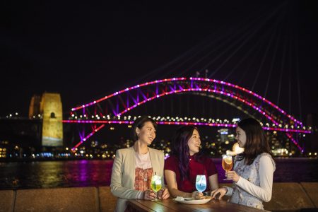 Friends enjoying Vivid cocktails at Opera Bar, Sydney Opera House during Vivid Sydney 2019.